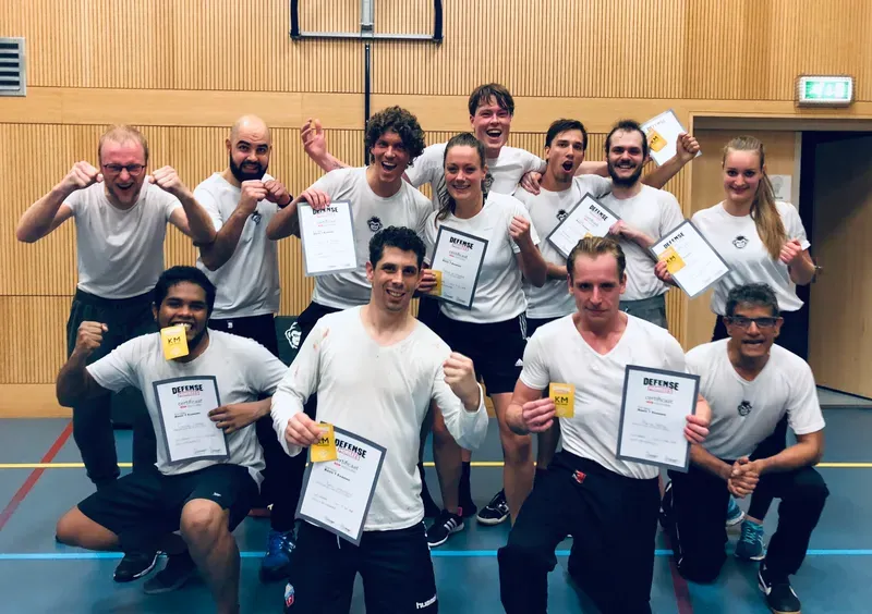 Groep DefenseMonkees-leden met hun Krav Maga-certificaten en patches na een examen