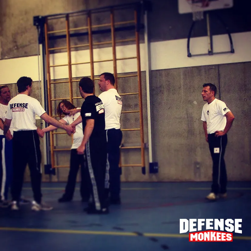 Groepsles Krav Maga bij Monkees: leden oefenen een techniek in tweetallen onder begeleiding van de instructeur